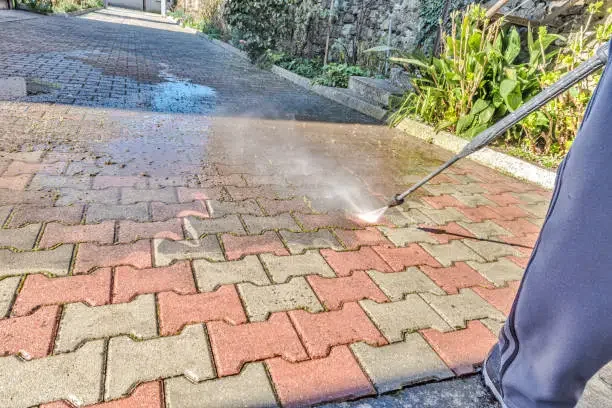 Pressure cleaning paving bricks — clean strip next to the dirty surface
